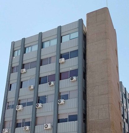 Modern multi-story office building with air conditioning units on the facade.